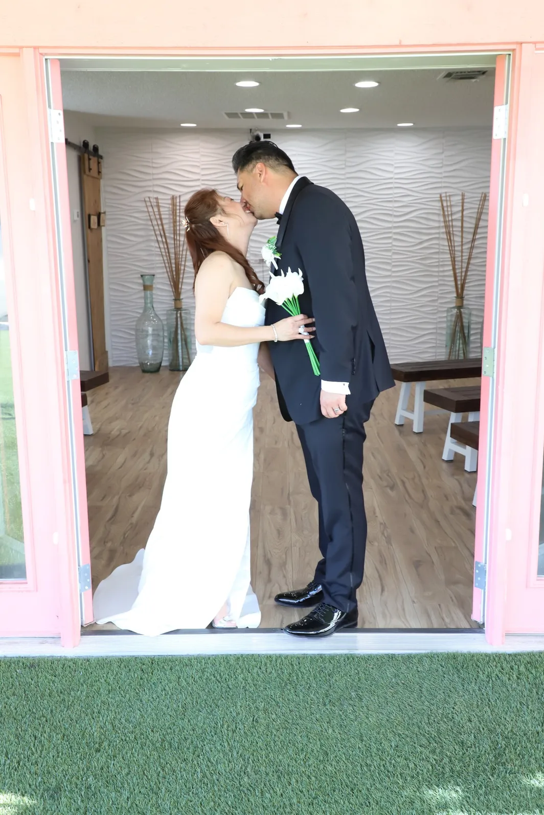 A newlywed couple shares a kiss at the pink chapel doors in Las Vegas.
